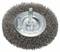 Une brosse métallique circulaire à grains moyens sur une plaque de métal, utilisée pour enlever la rouille ou la peinture des surfaces.