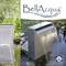 Une cascade moderne en acier inoxydable dans un jardin, à côté de roseaux et de pierres, portant l'inscription 'BellAcqua Waterfall'.