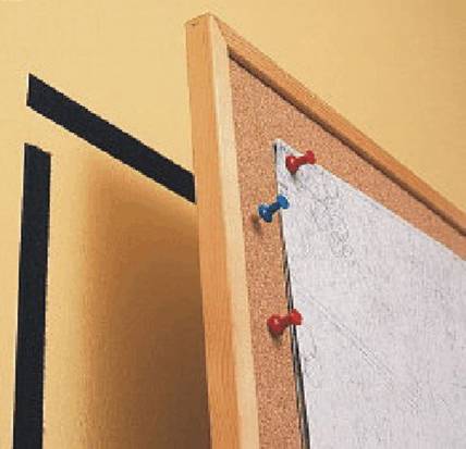 Un tableau d'affichage en liège sur un mur, portant une carte fixée par trois punaises rouges et bleues.