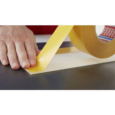 Une main applique du ruban adhésif jaune sur une surface plane.