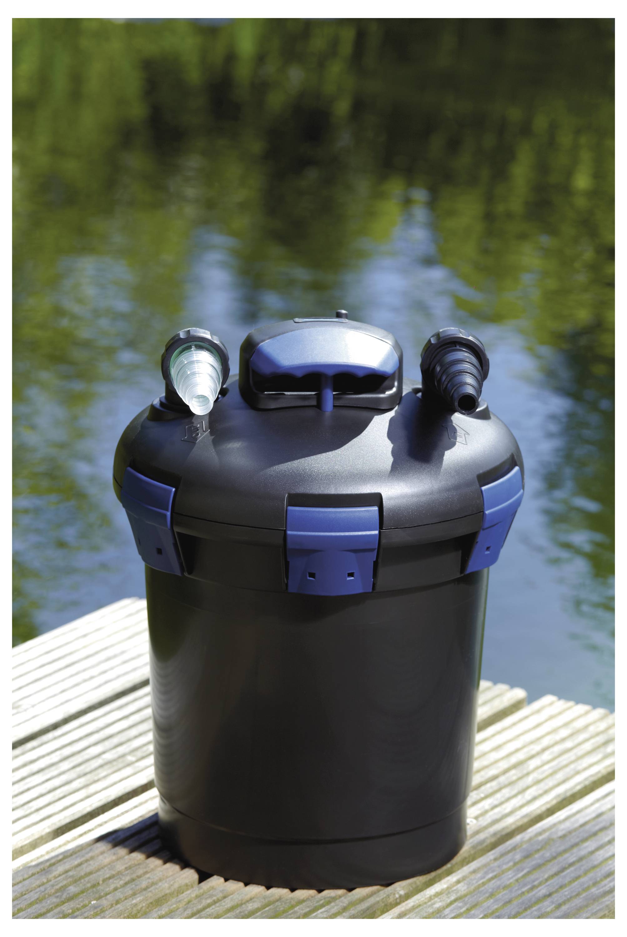 Filtre à eau cylindrique noir et bleu avec deux connecteurs sur une plateforme en bois près d'un étang.