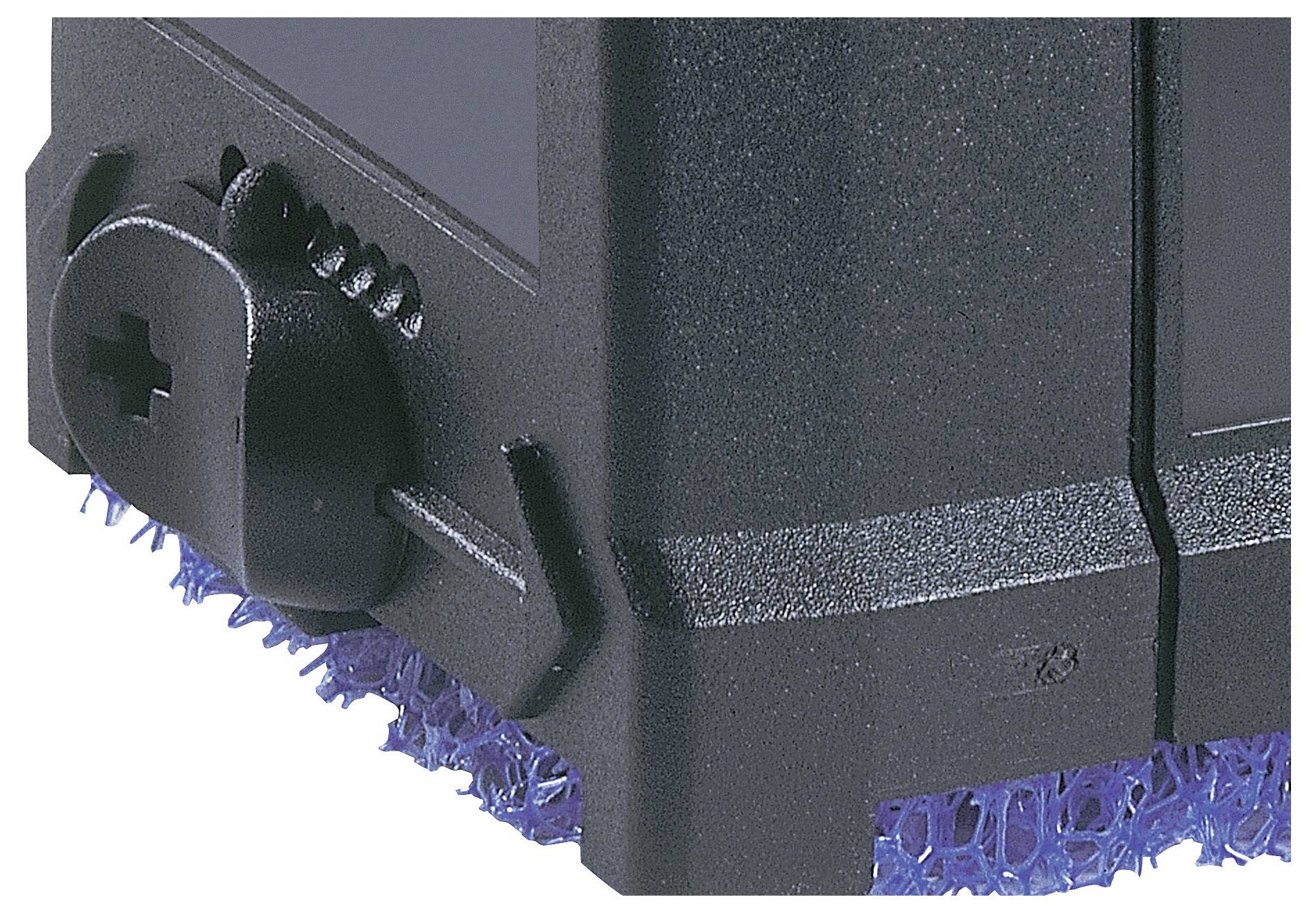 Un gros plan du coin d'un appareil électronique noir avec un rembourrage bleu texturé en dessous, mettant en vedette un bouton doté d'une vis à empreinte cruciforme.