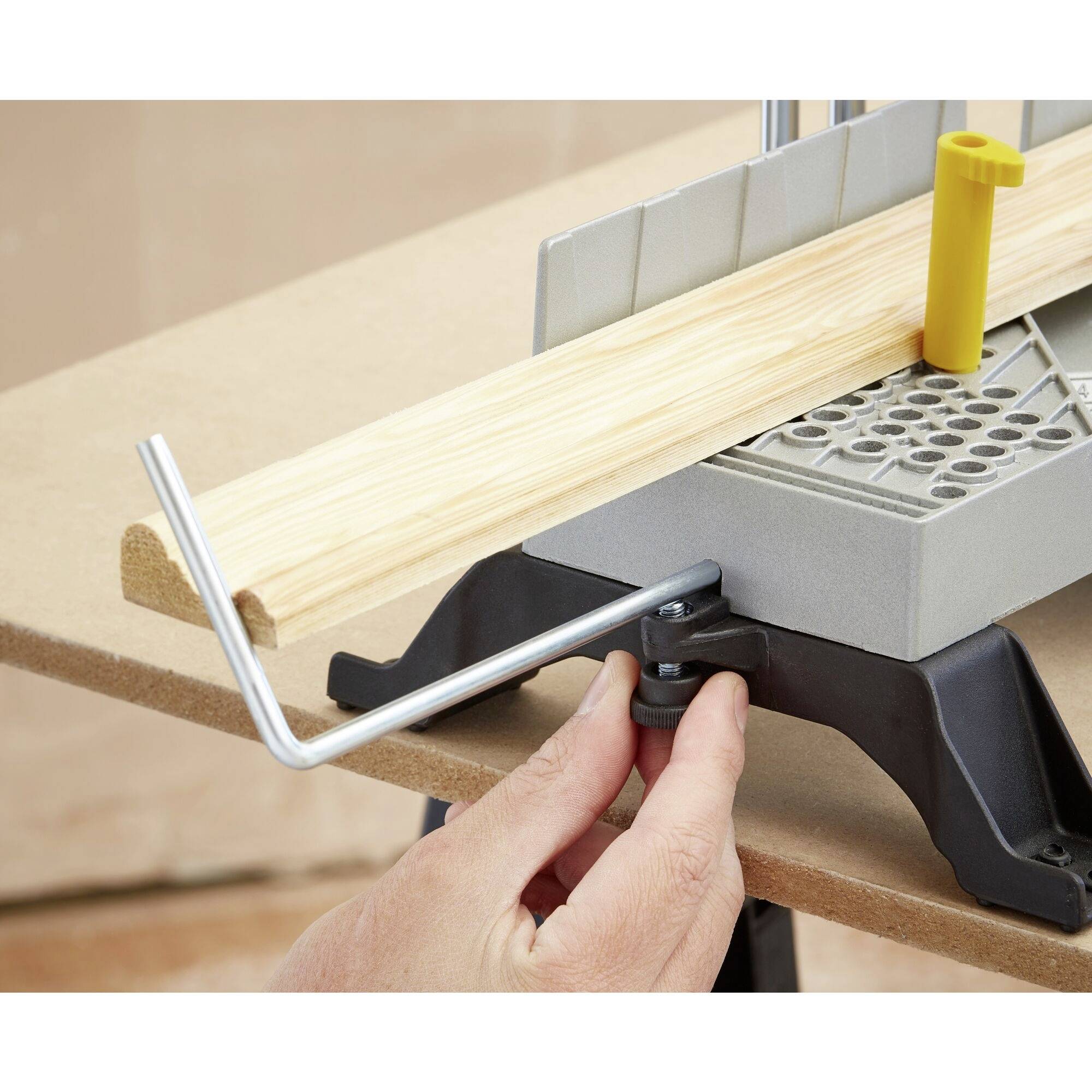 Une personne fixe une planche en bois dans un étau sur un établi afin de la maintenir solidement pour des travaux manuels.