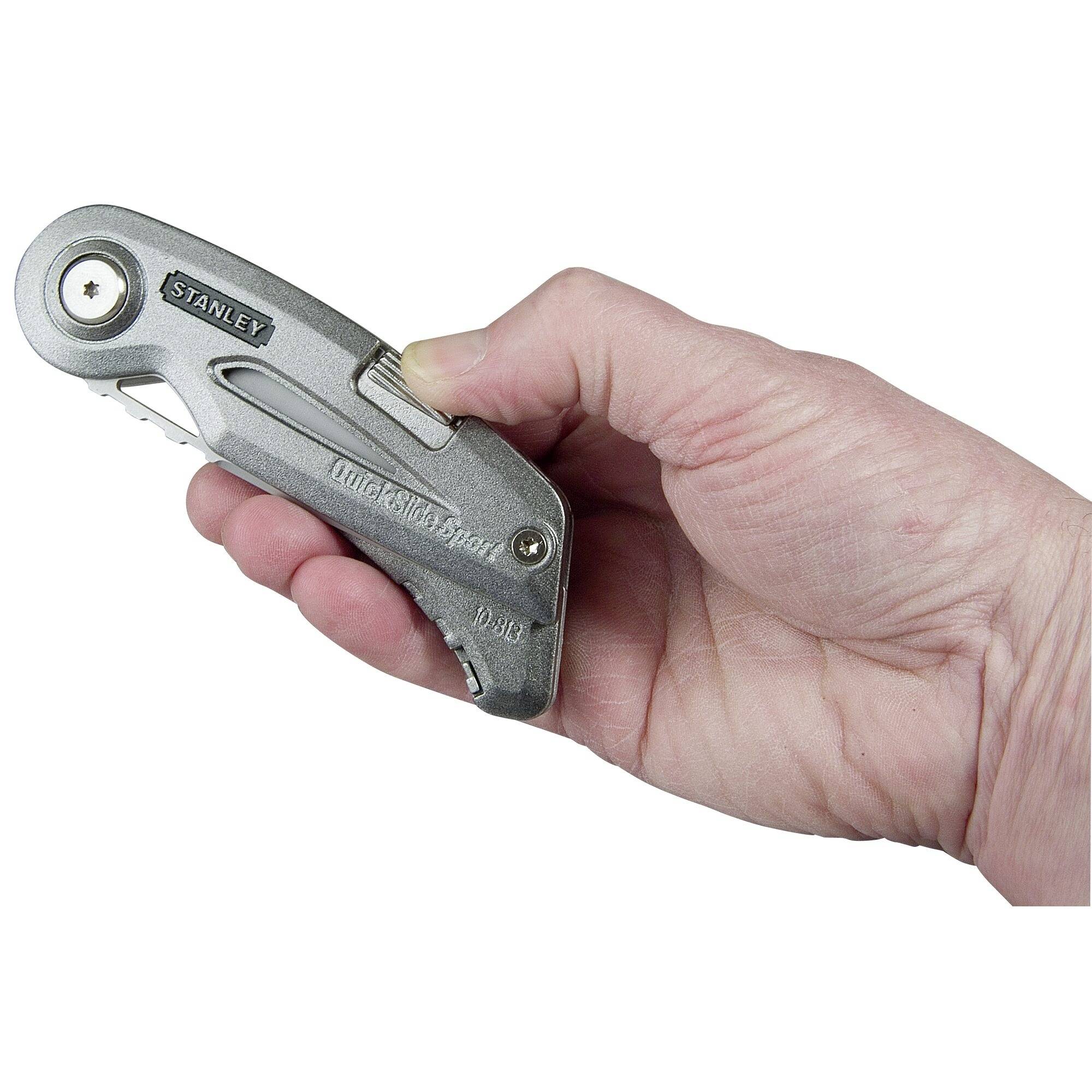 Une main tient un couteau universel Stanley argenté, prêt à être utilisé. Le couteau est replié et saisi dans la paume de la main.