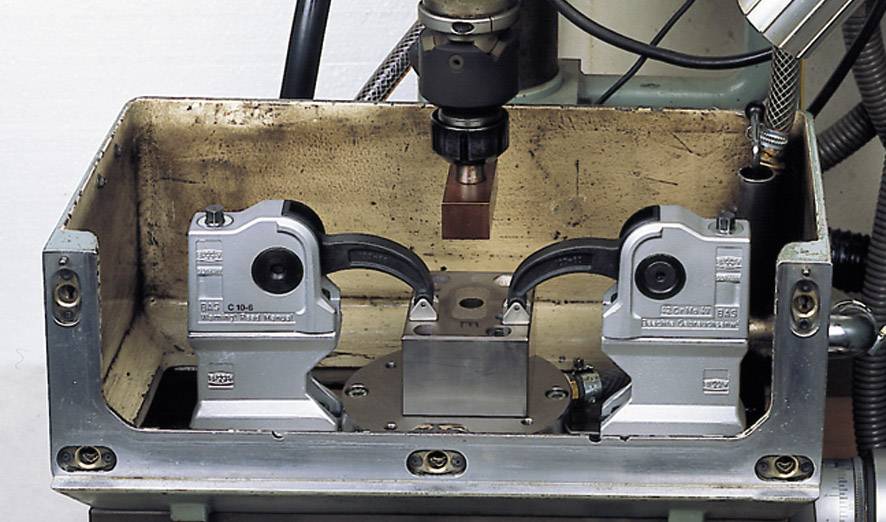 Machine de traitement des métaux avec boîtier de forme rectangulaire et deux supports pour un usinage précis. Outil de forage central visible.