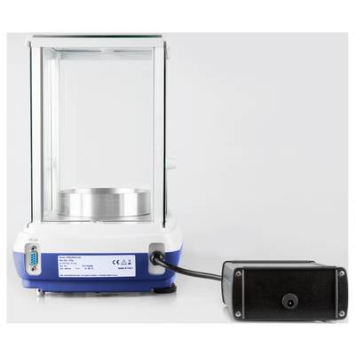 Une balance de laboratoire de précision avec un affichage numérique et une alimentation externe. La balance est posée sur une surface blanche.