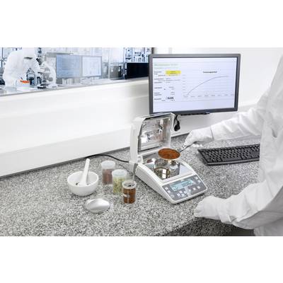 Un technicien de laboratoire pèse une substance sur une balance de précision. Un écran d'ordinateur affichant des données et un diagramme est visible en arrière-plan.