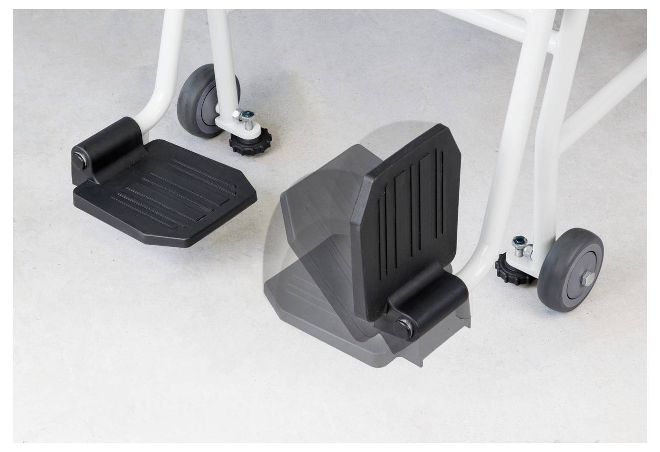 Des repose-pieds noirs pour fauteuil roulant sur un sol gris, avec des roues grises adjacentes sur un cadre blanc, illustrent l'équipement.