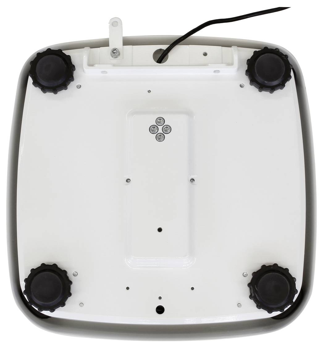 L'image montre le dessous d'un appareil carré avec quatre boutons noirs aux coins et un câble noir en haut.