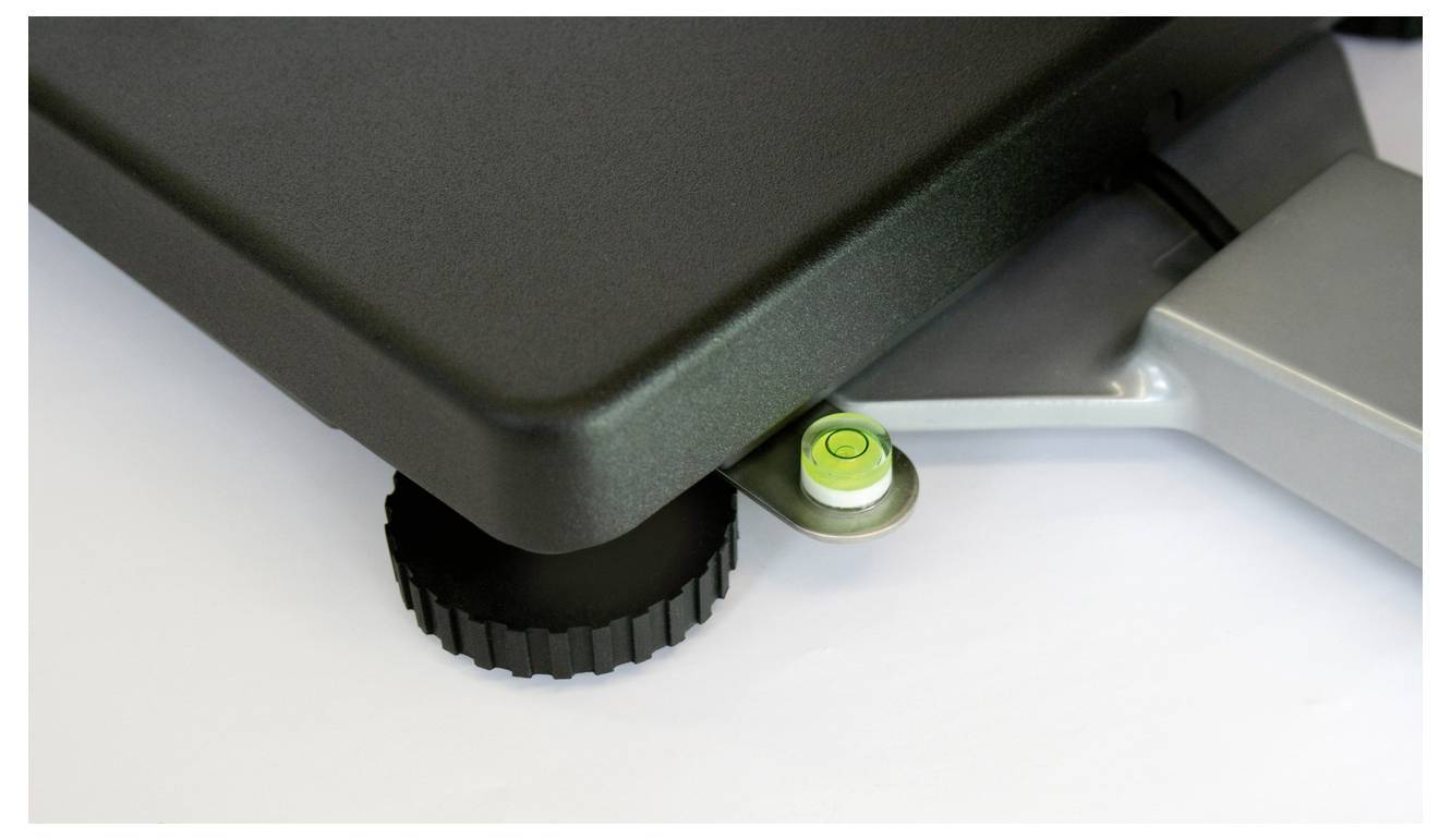 Un niveau à bulle posé sur une surface sombre montre son horizontalité grâce à une bulle d'air qui repose au centre du tube en verre.