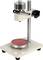 Un microscope de laboratoire avec un porte-objet rouge, des éléments de réglage en argent et en noir, monté sur un socle stable.