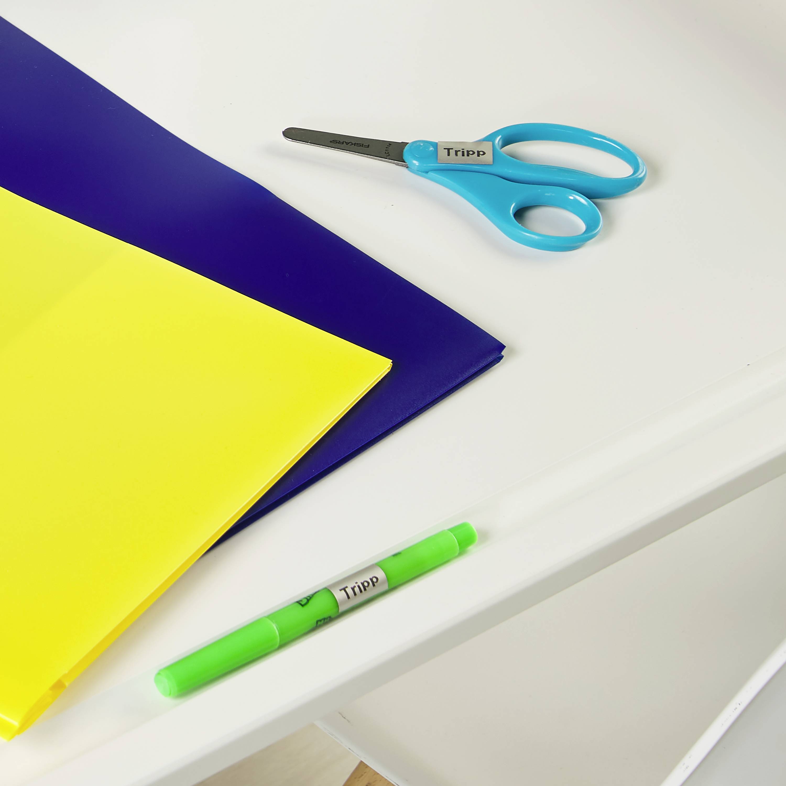 Bureau avec un dossier bleu et jaune, des ciseaux et un stylo vert.