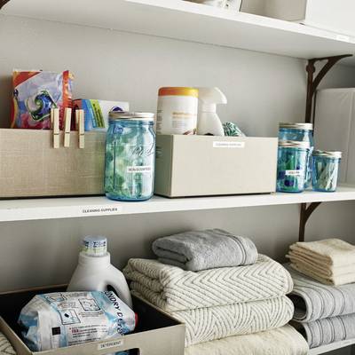 Étagères de rangement avec produits de nettoyage, serviettes et verres. Disposés de manière ordonnée avec des étiquettes.