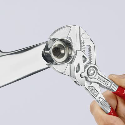 Une main tient une pince réglable qui serre un écrou sur une clé à molette. L'accent est mis sur la manipulation des outils.
