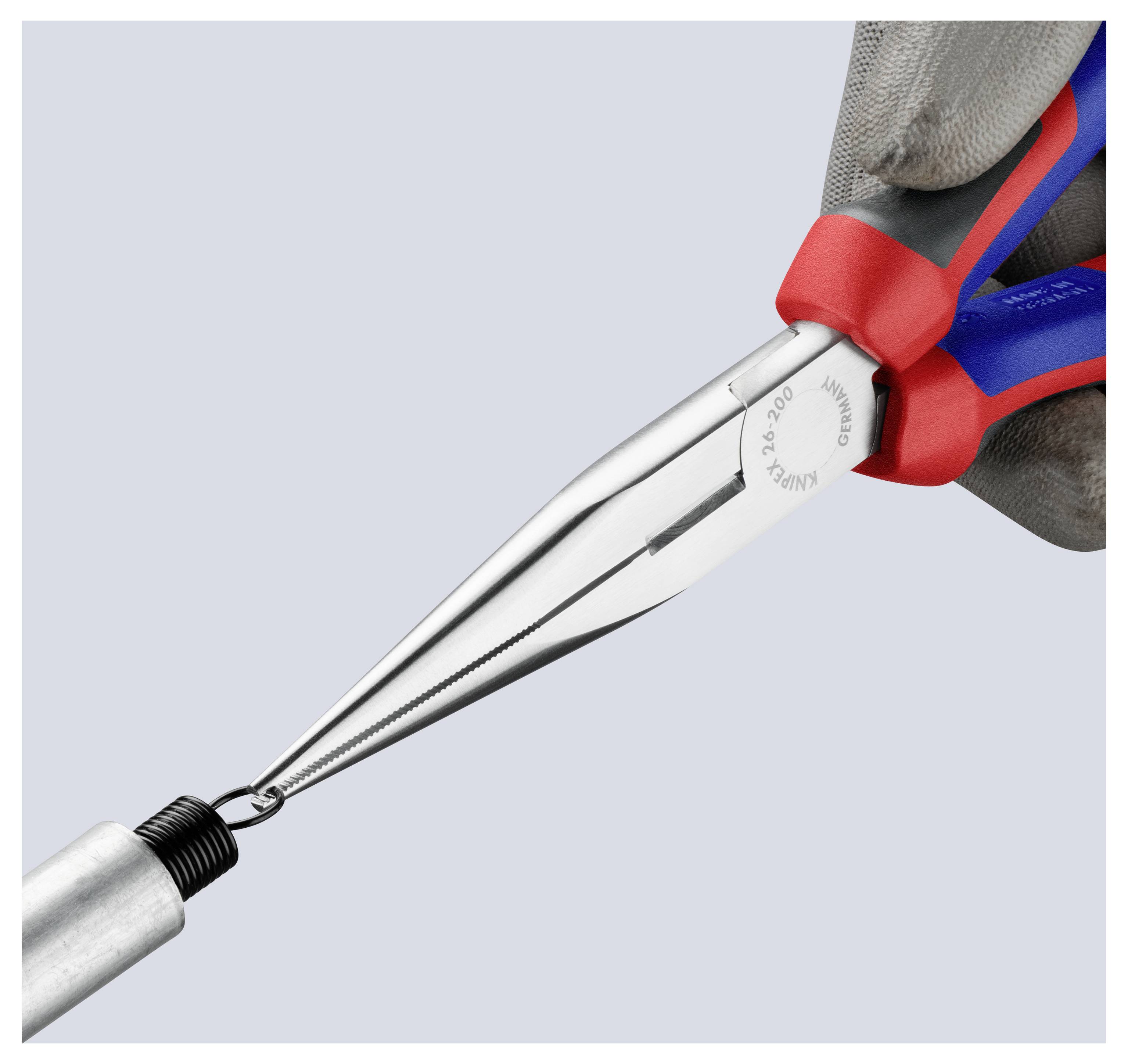 Une main gantée utilise une paire de pinces à long nez pour saisir une petite bobine métallique, démontrant la précision de l'outil et le contrôle de la prise.