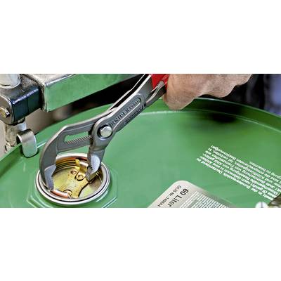 Une main utilise une clé à molette pour ouvrir le couvercle d'un fût vert. Le couvercle est en métal et la main semble puissante.