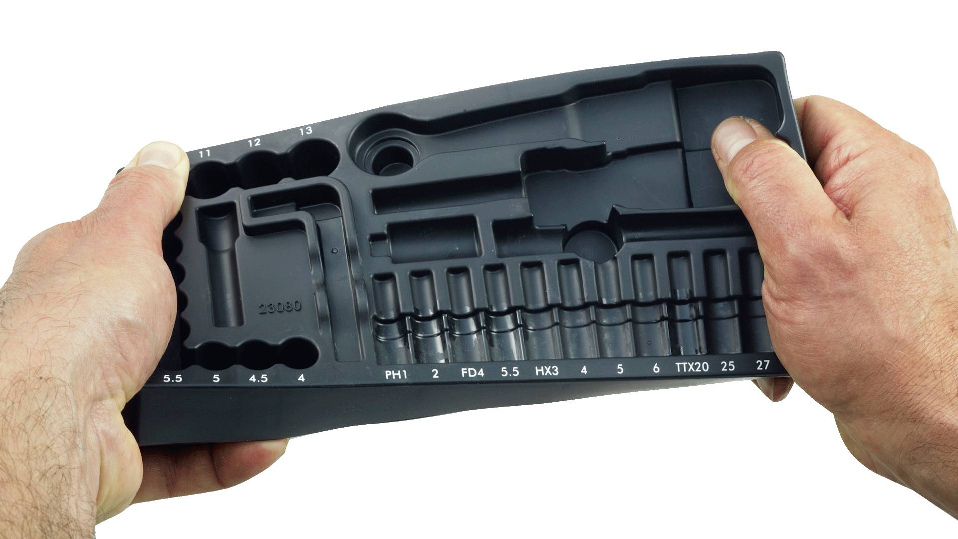 Deux mains tiennent un étui noir en plastique vide pour outils, comportant plusieurs compartiments destinés à différents embouts, étiquetés avec des numéros et des tailles.