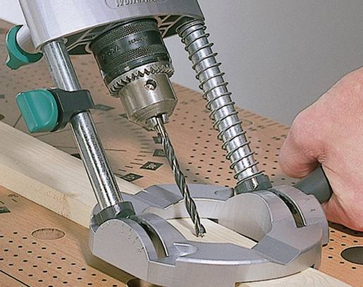 Une main utilise une perceuse sur une table en bois pour percer un trou dans un morceau de bois.