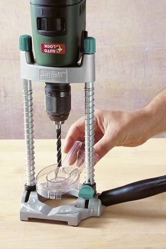 Une personne fixe une mèche dans un support de perceuse sur une table. D'autres mèches sont visibles en arrière-plan.