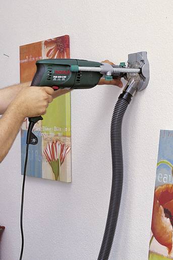 Une main tient un tuyau de cuivre sous un support de perceuse avec une perceuse. L'environnement est un établi clair.