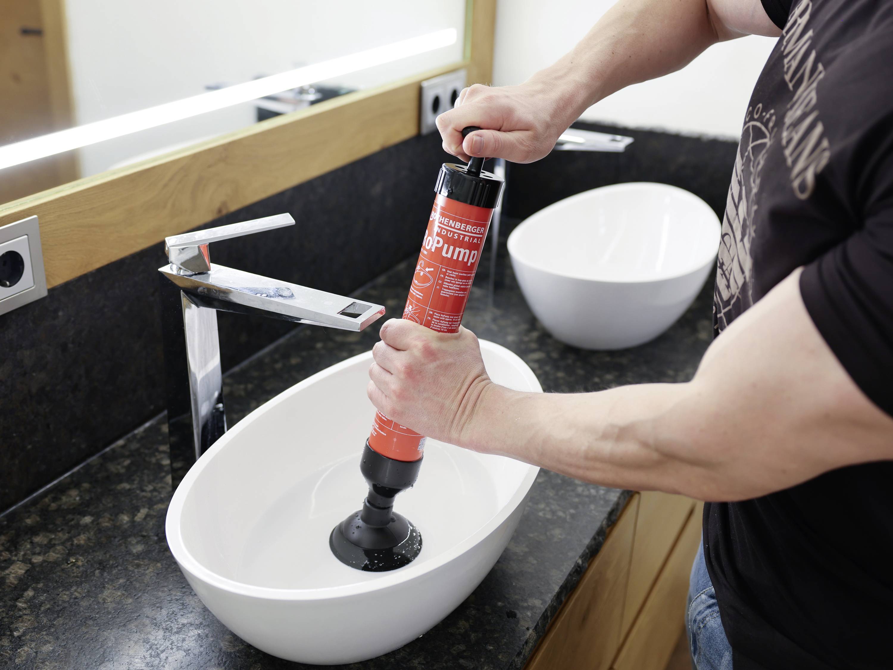 Une personne utilise un déboucheur à ventouse dans un lavabo de salle de bain pour éliminer un bouchon.