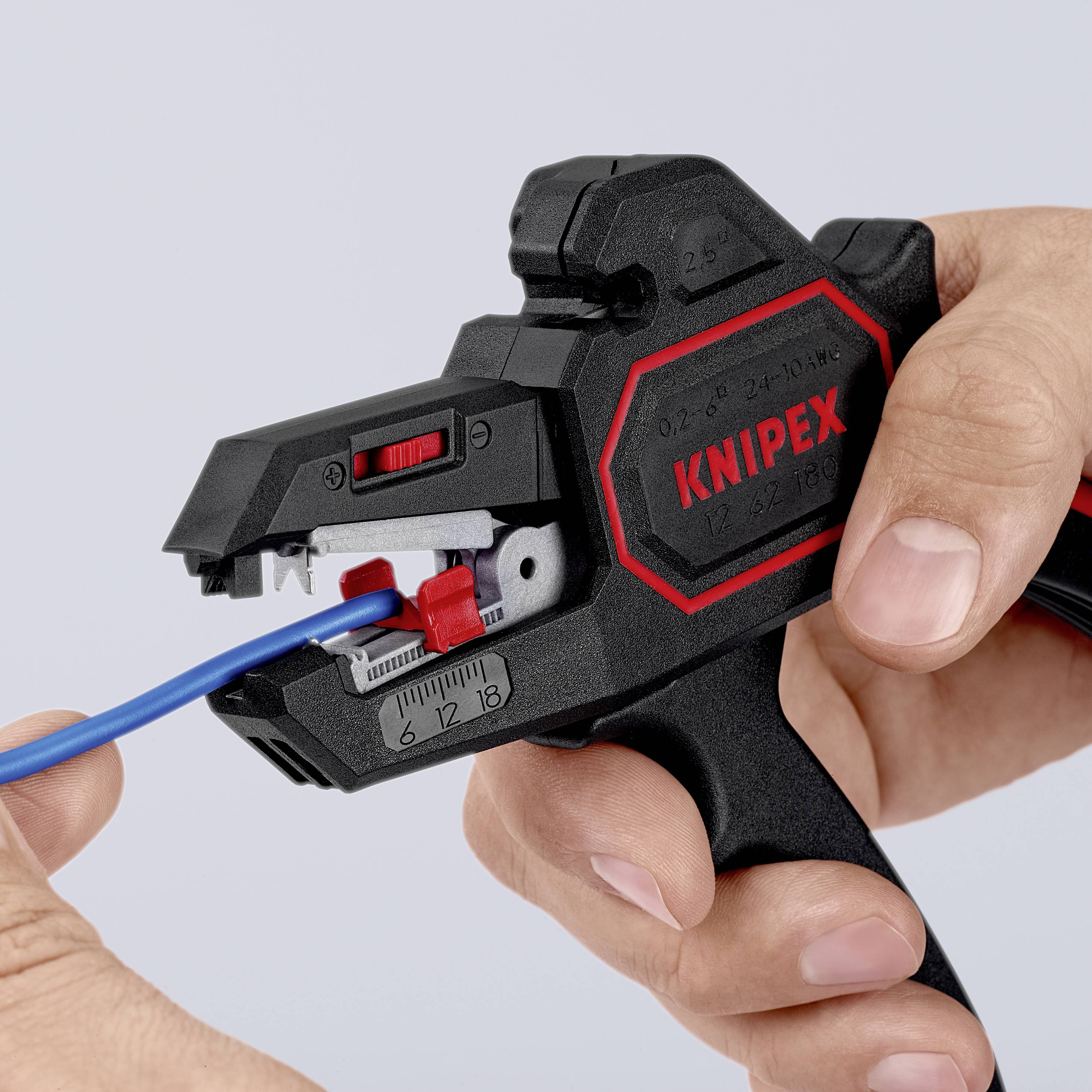 Une main utilise un dénudeur KNIPEX noir pour travailler un câble bleu. L'outil montre des échelles et des possibilités de réglage.