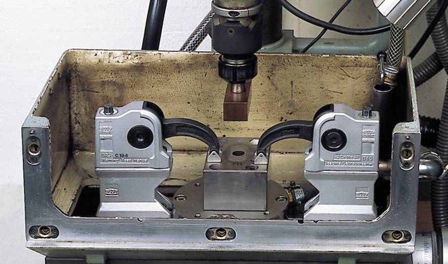 Une machine métallique équipée d'un outil pour l'usinage d'une pièce est visible, entourée de divers composants mécaniques.