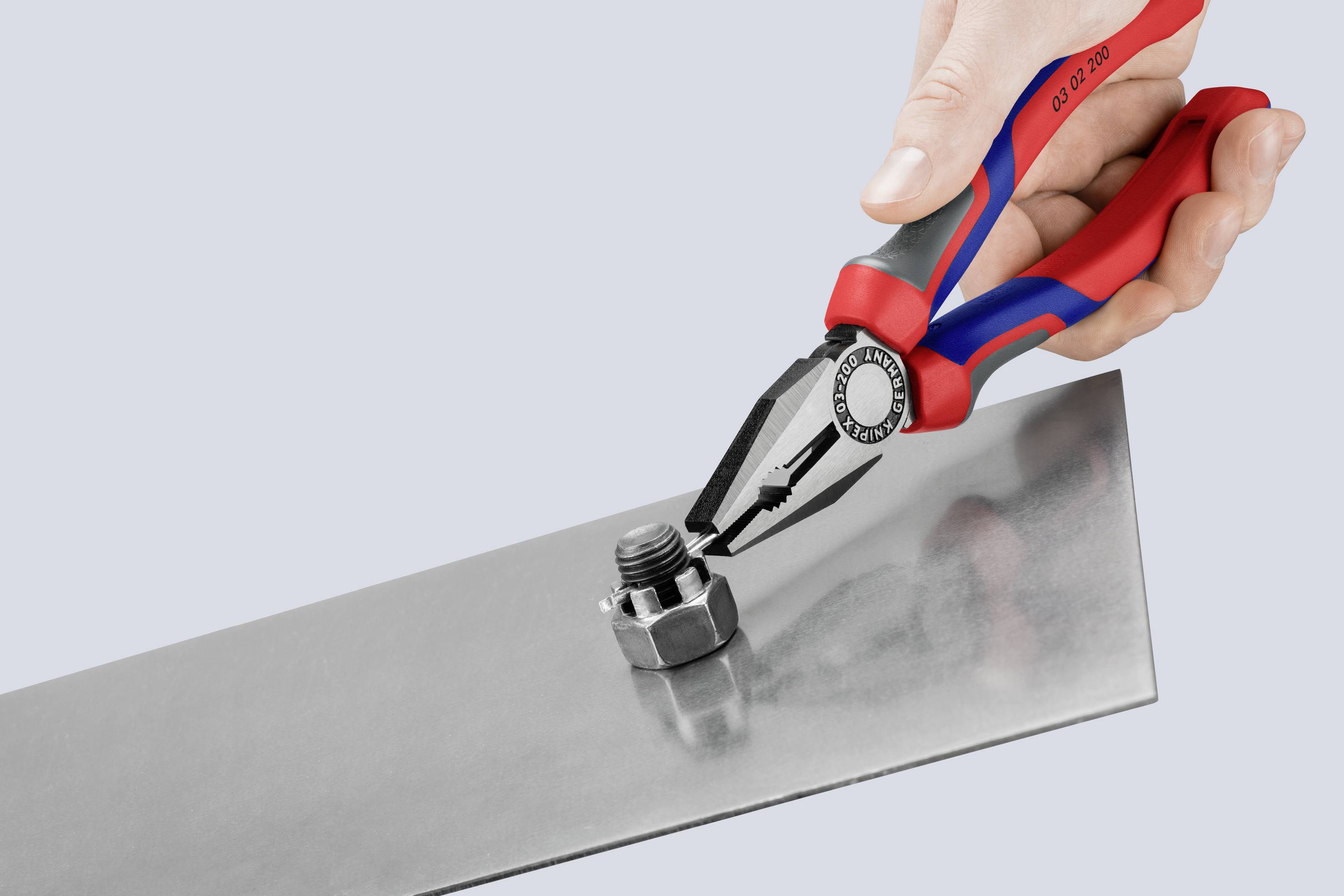 Une main tient une pince rouge et bleue qui saisit une vis sur une plaque métallique.
