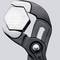 Une pince maintient un écrou hexagonal. La pince possède des surfaces de préhension dentelées pour une meilleure prise. L'arrière-plan est neutre.