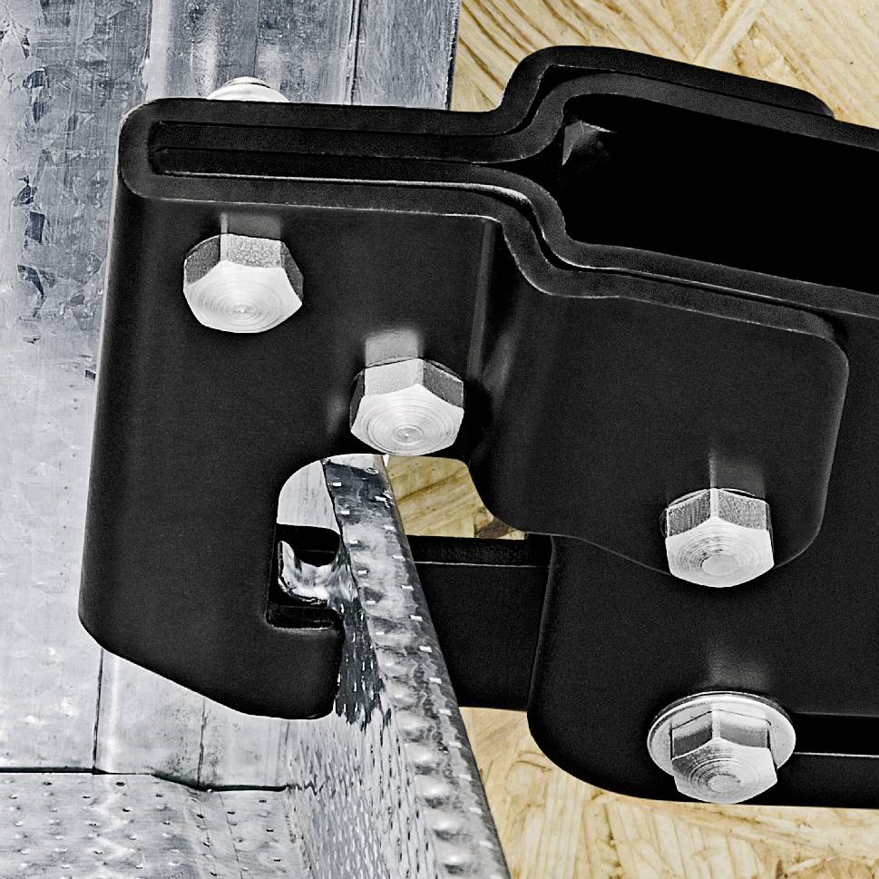 Un gros plan d'un ferrage métallique fixé sur une planche en bois. Le ferrage est maintenu par des vis.