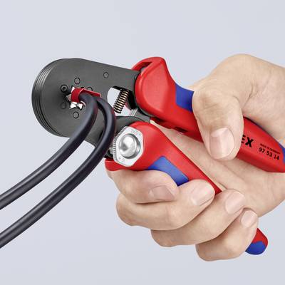 Une personne utilise une pince à dénuder rouge pour travailler les extrémités de deux câbles noirs. La pince retire l'isolation.