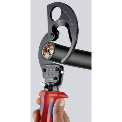 Une main tient une pince-ciseau Knipex en train de couper un câble épais. La poignée de la pince est rouge et bleue, et la tête de coupe est en métal noir.