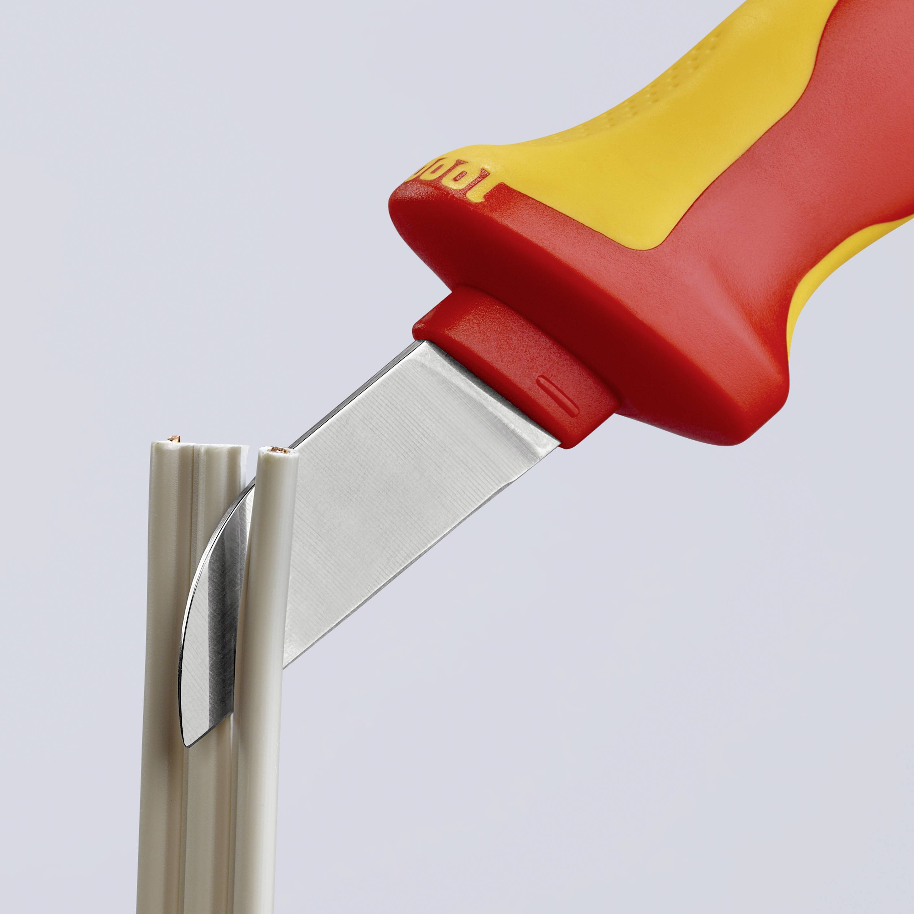 Un cutter à manche rouge coupe précisément un câble blanc.