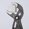 Une pince réglable maintient un cube métallique argenté dont la surface est brossée.