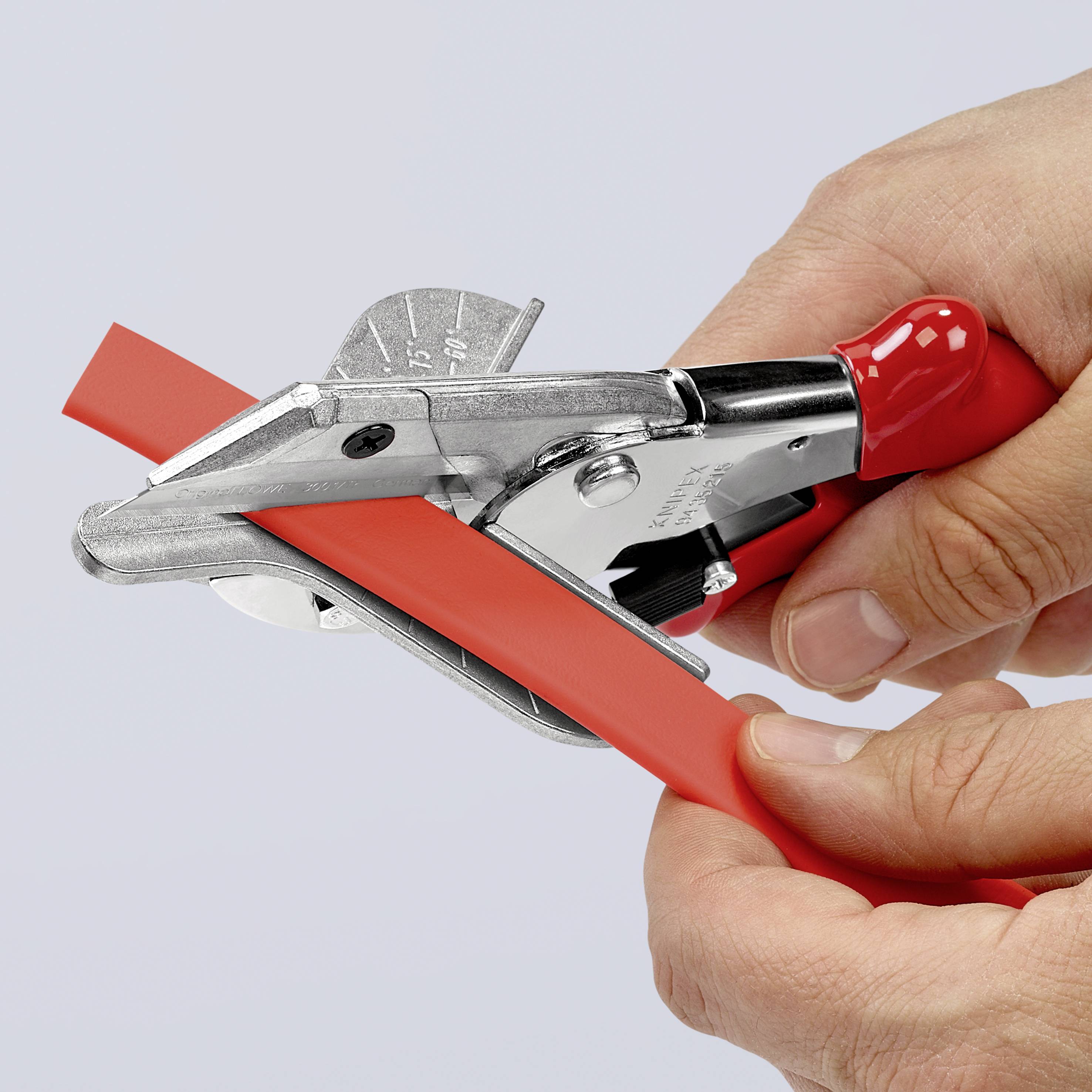 Une personne coupe un câble rouge avec un coupe-câble. Le coupe-câble a une poignée rouge et une lame argentée.