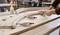 Scène de travail du bois avec deux mains travaillant sur une pièce de bois courbée, fixée à l'aide de serre-joints, à côté se trouve une bouteille de colle à bois.