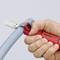 Une personne coupe un tube bleu clair à l'aide d'un outil rouge KNIPEX. L'image montre un gros plan du processus de coupe.