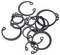 Une collection de circlips noirs de différentes tailles disposés de manière aléatoire, utilisés pour maintenir des goupilles dans des assemblages mécaniques.