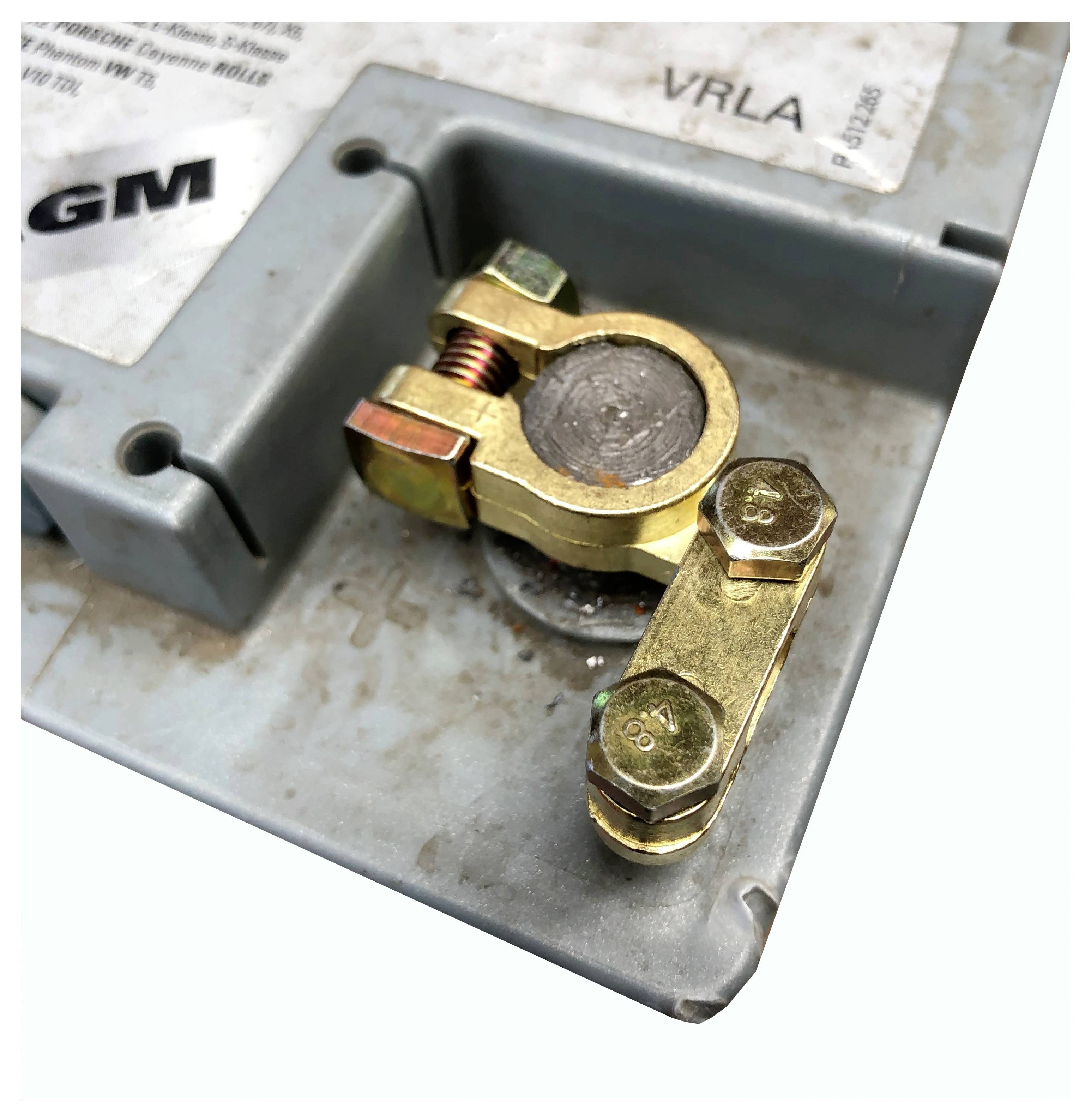 Un gros plan d'une borne de batterie montrant une pince en laiton fixée au pôle négatif sur le boîtier de la batterie.