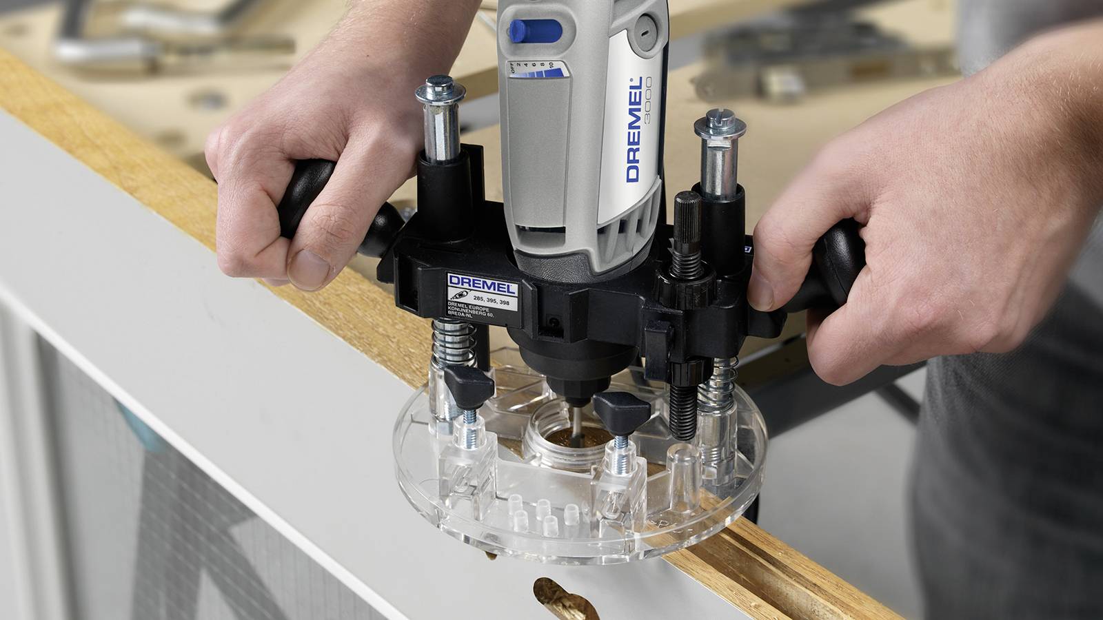 Une personne utilise un embout de fraise Dremel pour découper des formes précises dans un morceau de bois.