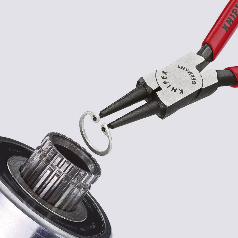 'La pince saisit avec précision une pièce métallique industrielle. Utilisation précise d'un outil dans une application technique.'