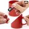 Deux mains appliquant de la colle liquide Pattex pour réparer l'anse cassée d'une tasse rouge. La bouteille de colle et la tasse sont mises en évidence dans l'image.
