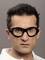 Une personne aux cheveux courts et sombres porte des lunettes de protection. L'arrière-plan est gris neutre.