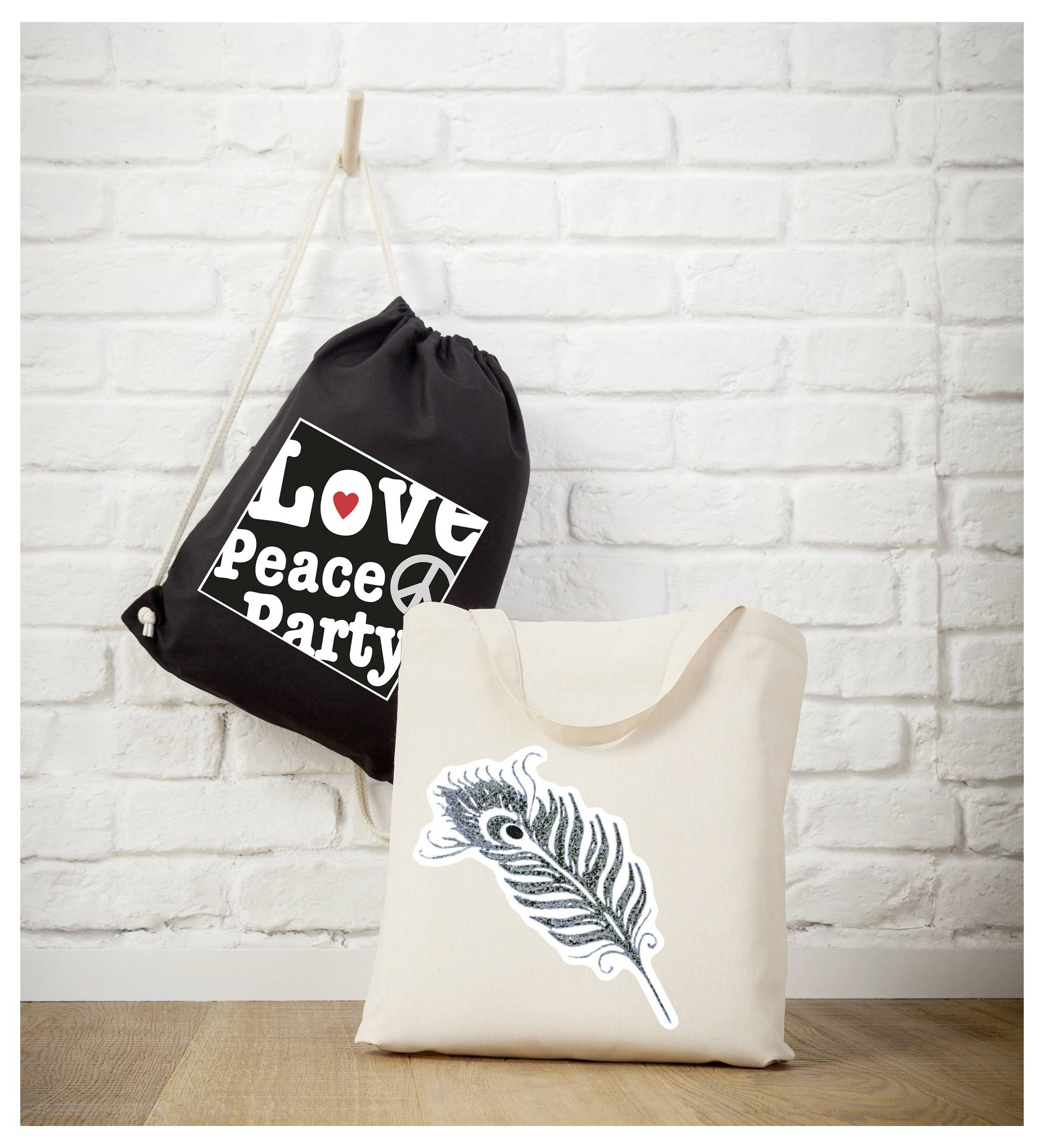 Deux sacs en tissu devant un mur de briques blanches : un sac à cordon noir avec l'impression 'Love Peace Party' et un sac couleur crème avec un motif de plume.