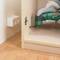 Une personne utilise un outil multifonction Bosch PMF 180 E pour travailler une étagère en bois. Une prise électrique est visible sur le mur.