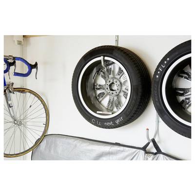 Mur de garage avec un vélo, deux pneus de voiture montés, et un objet couvert, suggérant un stockage ou une exposition de pneus.