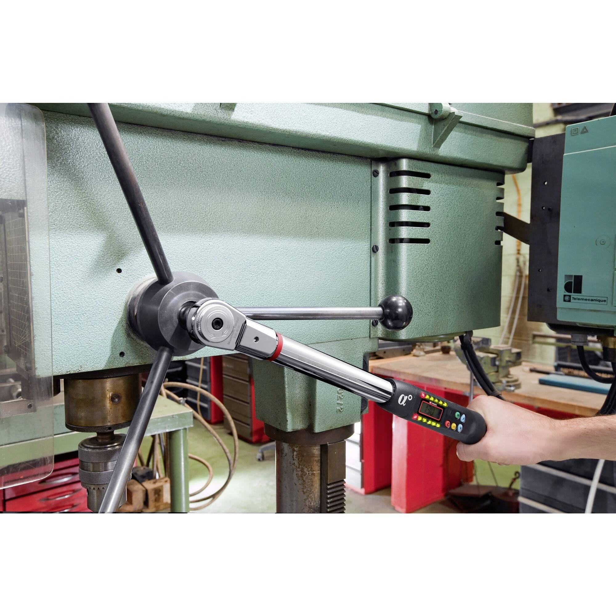 Une personne utilise une perceuse industrielle avec une clé dynamométrique pour garantir des réglages précis et un contrôle optimal.