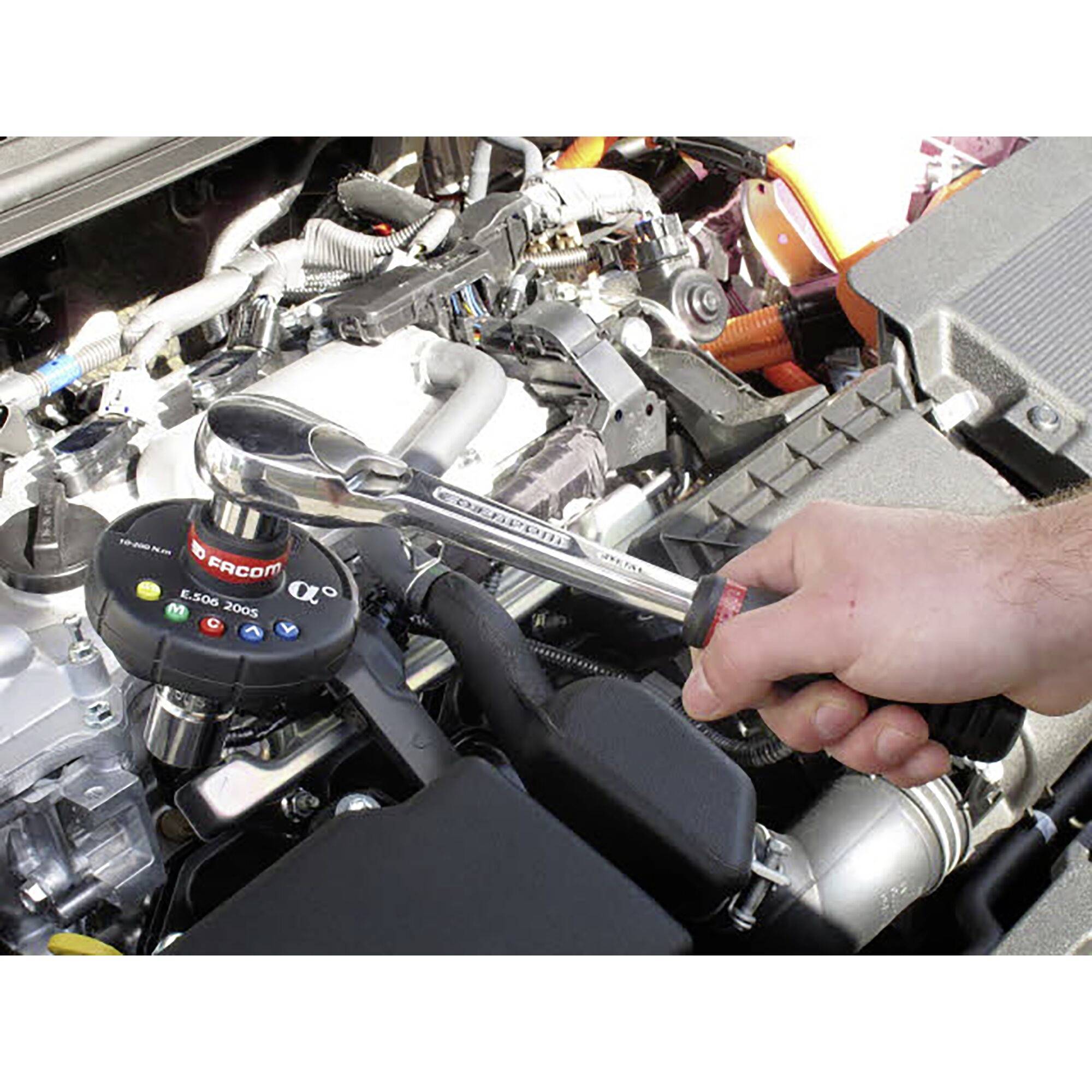 Une personne serre les vis d'une pièce automobile avec une clé dynamométrique dans le compartiment moteur d'un véhicule.