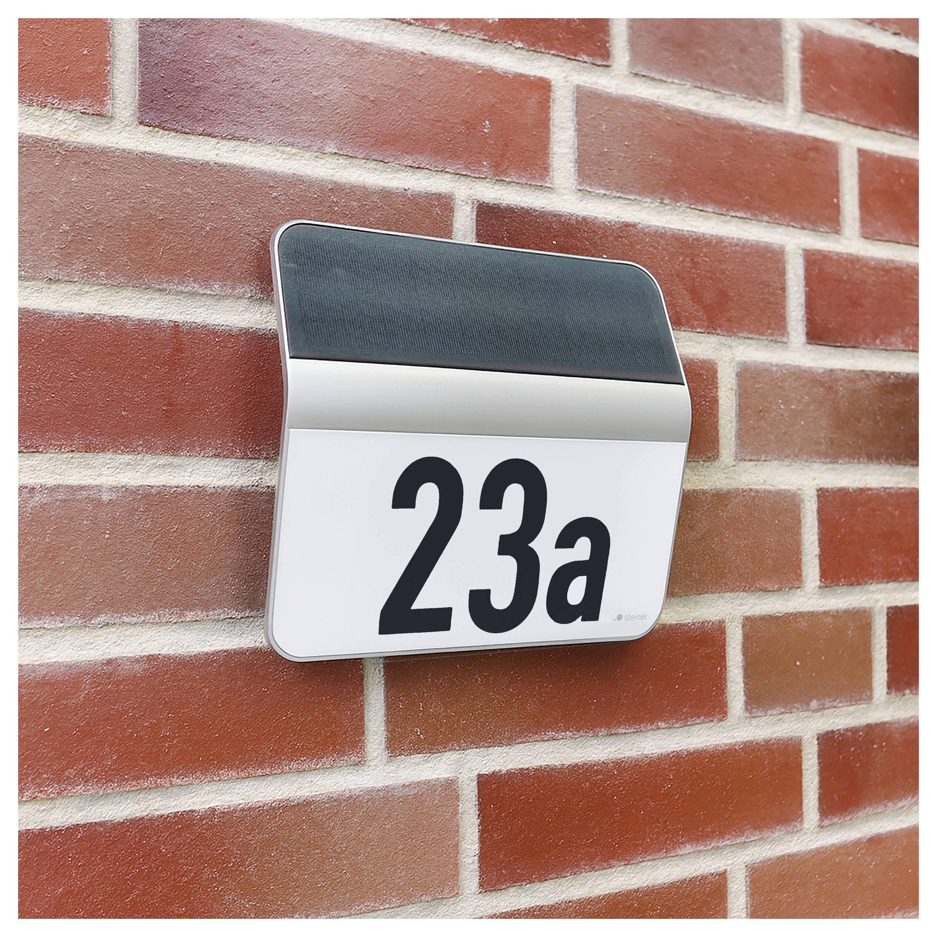 Plaque numéro de maison murale affichant « 23a » sur un mur de briques.
