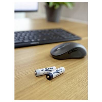 Deux batteries Ansmann AA sur un bureau en bois à côté d'une souris sans fil noire et d'un clavier.